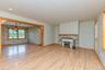 Unfurnished living room featuring baseboard heating, wood finished floors, baseboards, and wallpapered walls