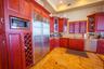 Kitchen featuring dark brown cabinets, stainless steel appliances, light stone countertops, tasteful backsplash, and glass insert cabinets