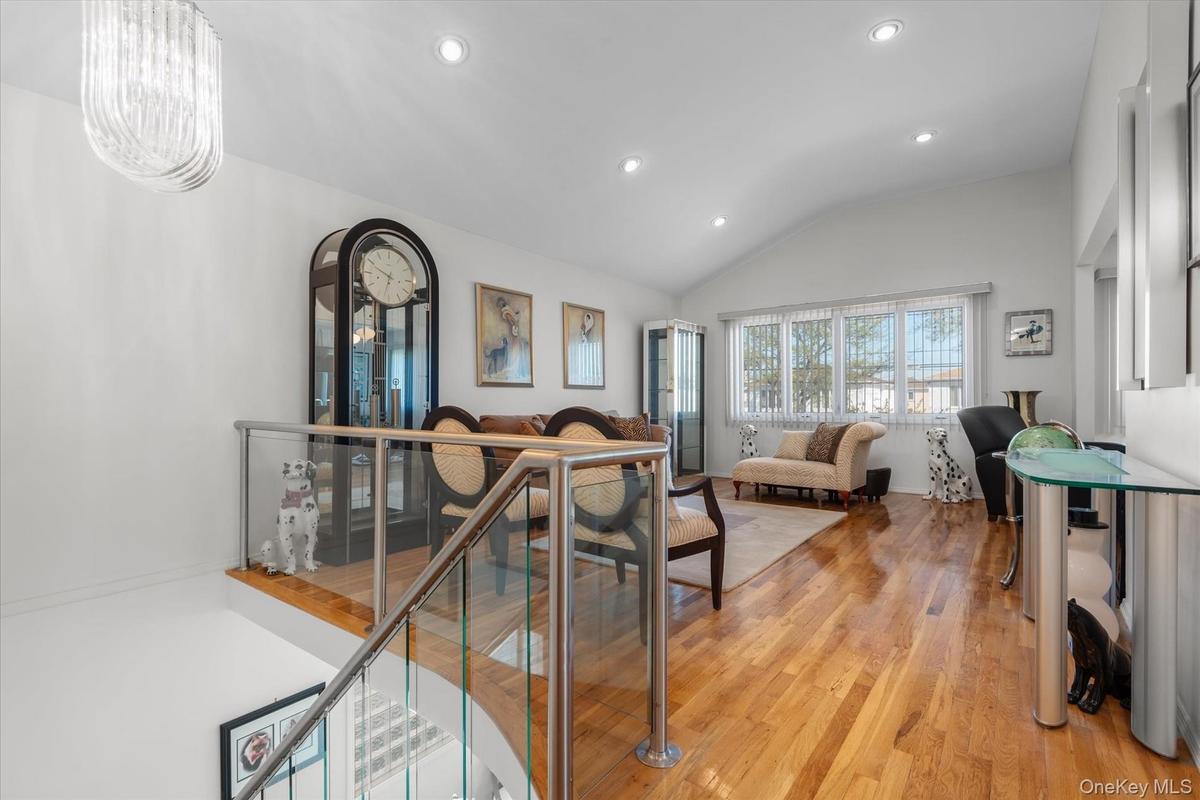 Living room featuring light hardwood / wood-style flooring, lofted ceiling, and a notable chandelier