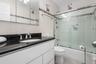 Full bathroom featuring vanity, backsplash, tile patterned floors, bath / shower combo with glass door, and tile walls