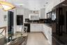 Kitchen featuring sink, white cabinets, decorative backsplash, light tile patterned flooring, and black appliances