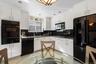 Kitchen with black appliances, white cabinetry, and sink