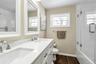Bathroom featuring double vanity, shower / bath combination with glass door, and dark wood finished floors