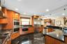 Kitchen with built in appliances, pendant lighting, dark stone countertops, wood finish cabinetry, and decorative backsplash