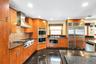 Kitchen with built in appliances, granite tiled floors, wood finish cabinetry, dark stone counters, and recessed lighting