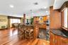 Kitchen with wood finish cabinetry, a kitchen breakfast bar, dark stone counters, hanging light fixtures, and stainless steel appliances