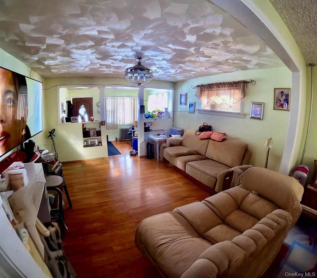 Living area with wood finished floors, radiator heating unit, and hanging lights