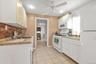 Kitchen featuring white appliances, light countertops, light tile patterned floors, ceiling fan, and white cabinetry