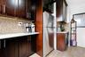 Kitchen with decorative backsplash, freestanding refrigerator, light stone countertops, and dark brown cabinetry