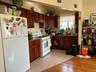 Kitchen with white appliances, light tile patterned floors, a wall mounted AC, dark stone countertops, and dark brown cabinets