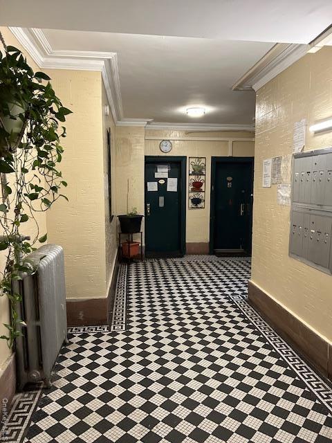 Hallway featuring radiator, mail area, and ornamental molding
