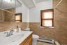 Full bath with vanity, a baseboard heating unit, tiled shower, tile walls, and light tile patterned flooring