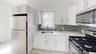 Kitchen with stainless steel appliances, white cabinets, light stone countertops, decorative backsplash, and light tile patterned flooring