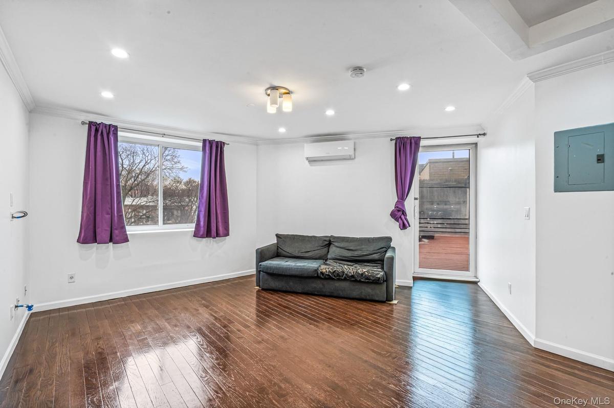 Living area with ornamental molding, electric panel, dark wood-style flooring, recessed lighting, and a wall mounted air conditioner