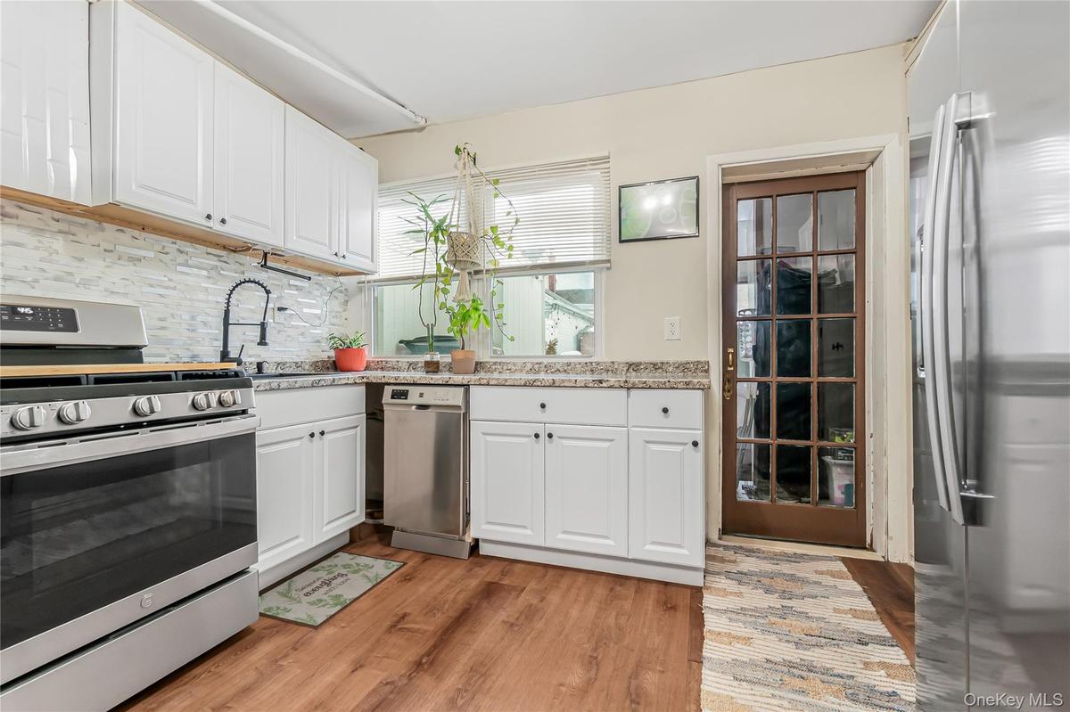 Kitchen with stainless steel appliances, white  shaker style cabinets, and light wood-style floors