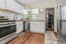 Kitchen featuring stainless steel appliances, white Shaker style cabinetry, and light wood-type flooring