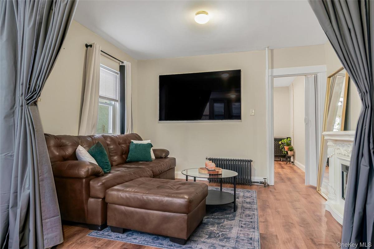 Living area featuring radiator heating unit, wood finished floors, and a fireplace