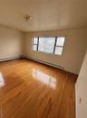 Empty room featuring hardwood / wood-style floors and a baseboard radiator