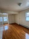 Unfurnished bedroom featuring multiple windows, baseboard heating, and wood-type flooring
