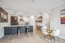 Kitchen with white cabinetry, wall chimney exhaust hood, built in fridge, kitchen peninsula, and decorative light fixtures