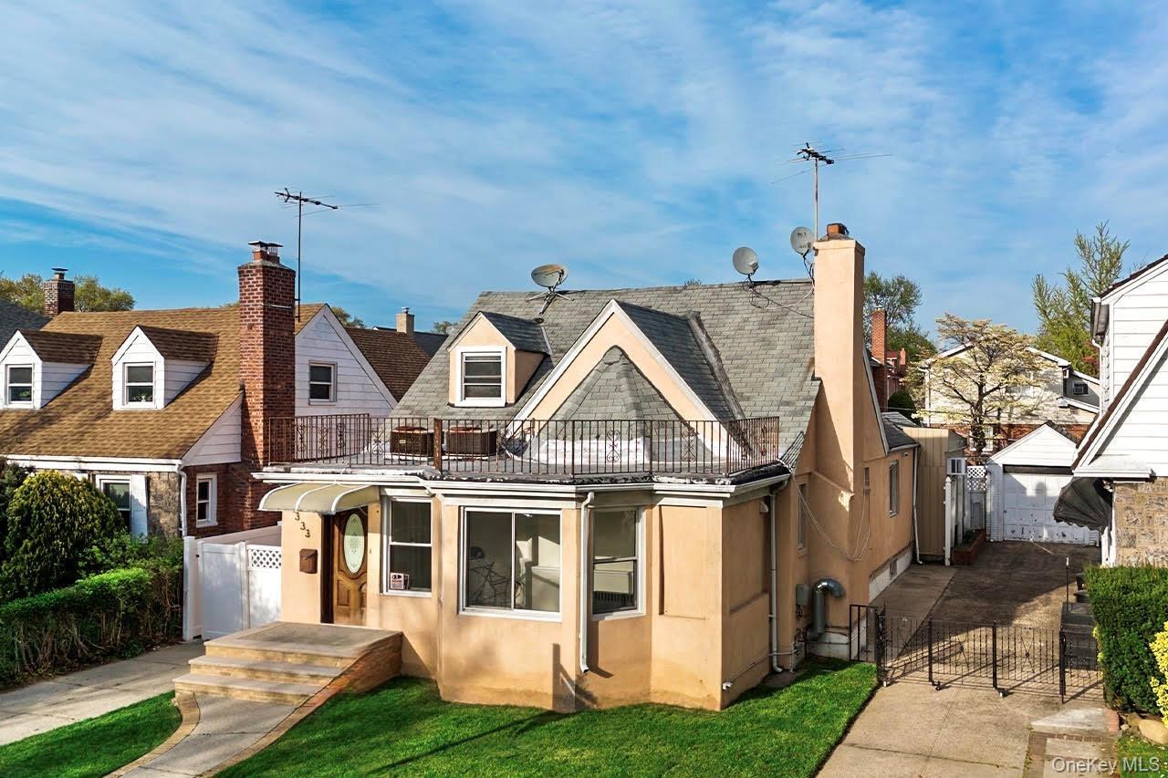 Front view of house with a chimney, fence, a balcony, and stucco siding