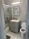 Bathroom with vanity, tile walls, combined bath / shower with glass door, and light marble finish flooring