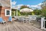 Expansive mahogany deck featuring an inviting outdoor dining area with seamless access through sliding glass door.