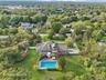 A picturesque view showcasing the swimming pool, sunlit patio, and hot tub, all set within a private fenced backyard and complemented by a balcony ove