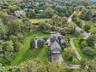 Aerial side perspective showcasing the property’s two-car attached garage and surrounding landscape. Virtually Staged to show opened pool.