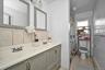 Full bathroom featuring baseboard heating, light tile patterned flooring, a shower with curtain, double vanity, and backsplash