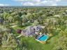 From the rear, the home reveals its inviting charm—complete with a fenced backyard, elegant chimney, and sunroom that seamlessly connects to the mahog