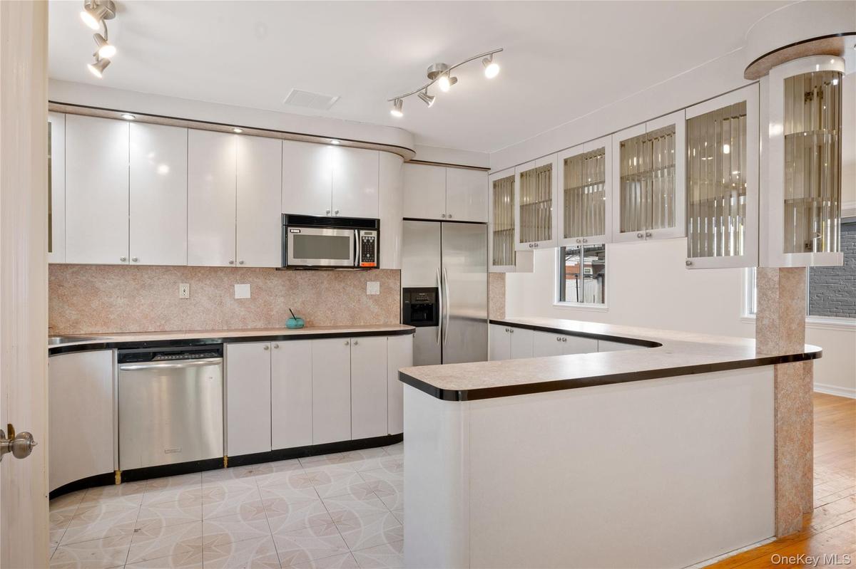 Kitchen featuring white cabinets, backsplash, visible vents, glass insert cabinets, and appliances with stainless steel finishes