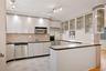 Kitchen featuring white cabinets, backsplash, visible vents, glass insert cabinets, and appliances with stainless steel finishes