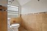 Bathroom with tile walls, lofted ceiling, and toilet