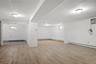 Below grade area featuring a baseboard heating unit, baseboards, wood finished floors, and a wall mounted air conditioner
