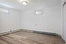 Basement with wood finished floors, a baseboard radiator, and crown molding