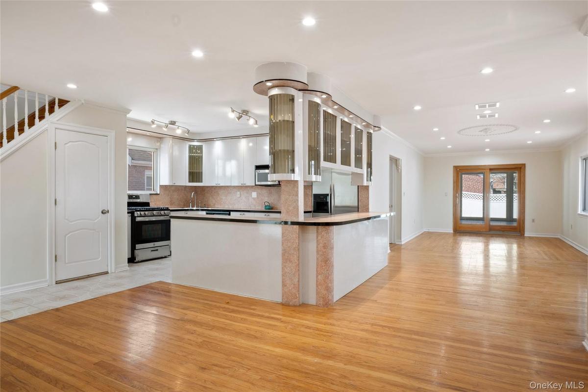 Kitchen featuring a sink, light wood-type flooring, glass insert cabinets, appliances with stainless steel finishes, and ornamental molding