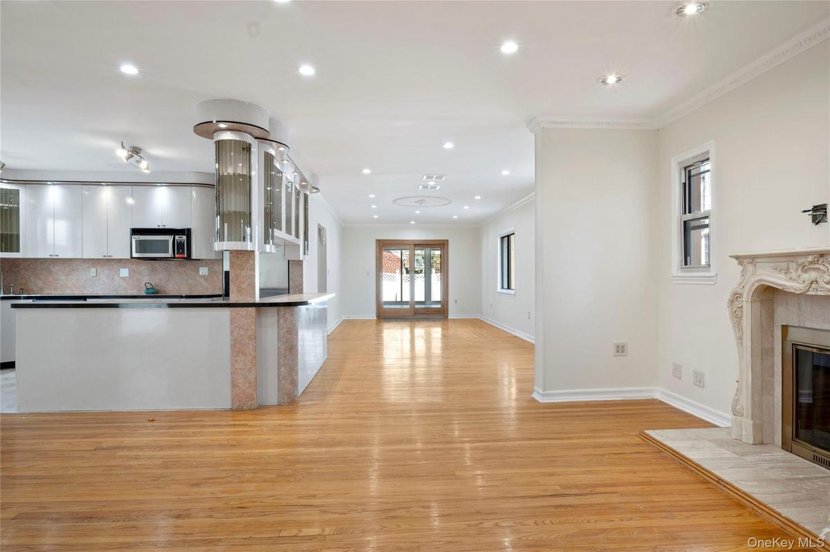 Kitchen featuring crown molding, a fireplace, white cabinets, stainless steel microwave, and light wood-style floors