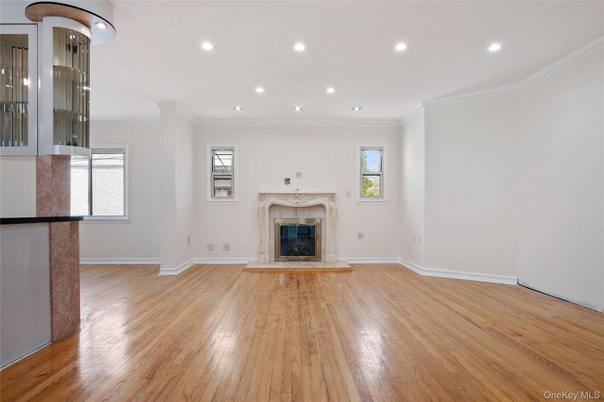 Unfurnished living room featuring crown molding, a high end fireplace, light wood-style floors, baseboards, and recessed lighting
