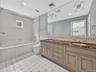 Full bath with double vanity, tiled shower / bath, tile patterned floors, and recessed lighting
