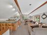 Living area with track lighting, light carpet, healthy amount of natural light, and bar