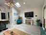 Living room with a skylight, high vaulted ceiling, wood finished floors, and recessed lighting