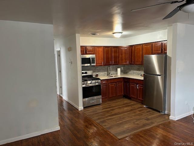 Kitchen featuring appliances with stainless steel finishes, light countertops, a ceiling fan, dark wood finished floors, and tasteful backsplash