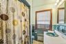 Bathroom with radiator, vanity, a shower with shower curtain, tile walls, and wainscoting