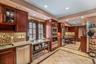 Kitchen featuring inlaid floor details, stainless steel appliances, glass insert cabinets, light stone counters, and recessed lighting