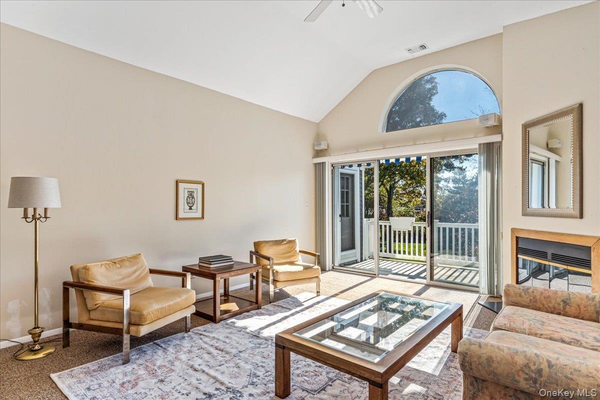 Carpeted living area featuring high vaulted ceiling and ceiling fan