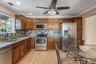 Kitchen featuring stainless steel appliances, light stone countertops, crown molding, decorative backsplash, and brown cabinetry