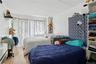 Bedroom with a textured ceiling, a baseboard heating unit, and wood finished floors