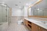 Bathroom with double vanity, a wainscoted wall, tile walls, a stall shower, and recessed lighting