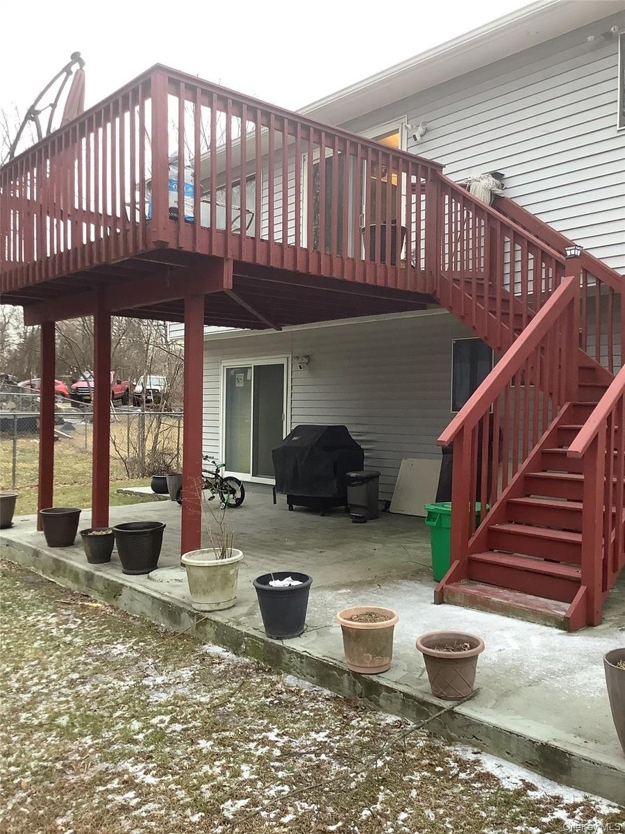 Snow covered patio featuring area for grilling and a wooden deck